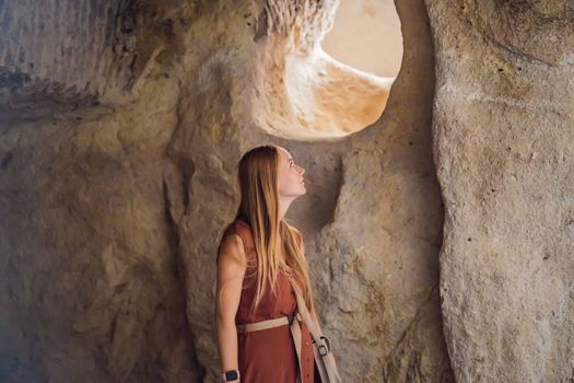 Young woman exploring valley with rock formations and fairy caves near Goreme in Cappadocia Turkey.