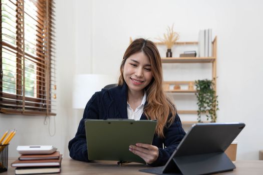 Asian woman Using laptop computer and working at office with calculator document on desk, doing planning analyzing the financial report, business plan investment