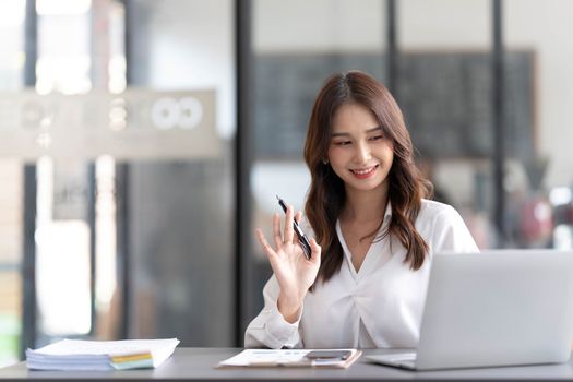 Young beautiful asian businesswoman working on tablet with happiness while sitting at the table in modern office room...