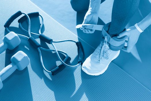 Woman putting on ankle wights before she starts a workout in a gym, health and fitness