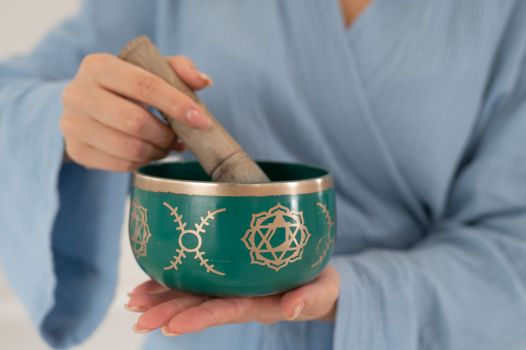 Asian woman playing Tibetan singing bowl