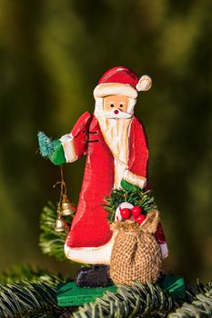 A laughing wooden Santa Claus isolated in front of a green coniferous forest