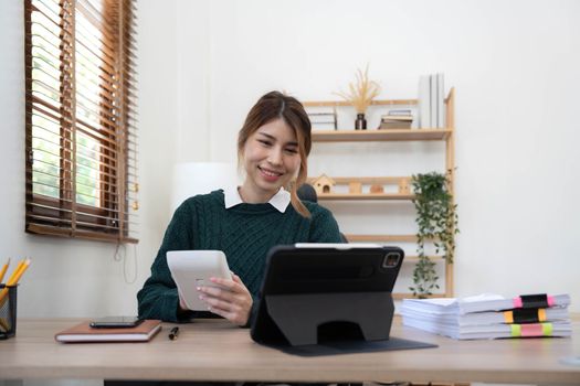 Portrait of smiling beautiful business asian young woman working in office use computer with copy space