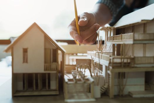 Engineers are consulting the team to design an architectural structure for clients with blueprints and building models to work at office.