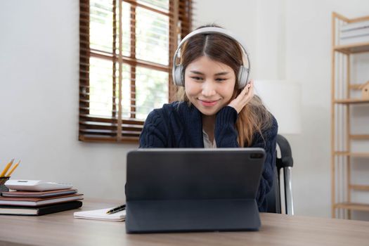 smiling girl relaxing at home She is listening to music using her laptop and wearing white headphones