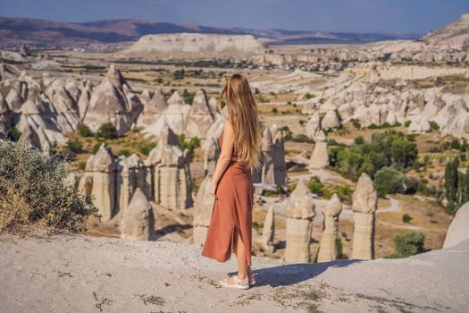 Young woman exploring valley with rock formations and fairy caves near Goreme in Cappadocia Turkey.