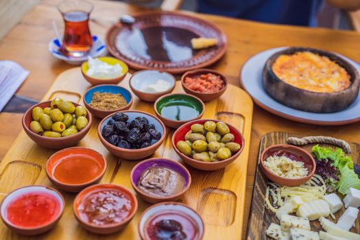 Turkish breakfast table. Pastries. Vegetables. Olives. Cheeses, fried eggs. Jams, tea in copper pot and tulip glasses. Wide composition.