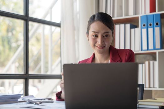 Beautiful young Asian girl working at a office space with a laptop. Concept of smart female business