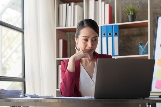 Beautiful young Asian girl working at a office space with a laptop. Concept of smart female business