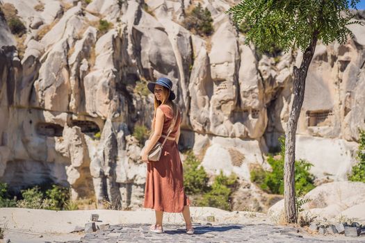 Young woman exploring valley with rock formations and fairy caves near Goreme in Cappadocia Turkey.