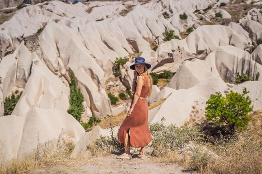 Young woman exploring valley with rock formations and fairy caves near Goreme in Cappadocia Turkey.