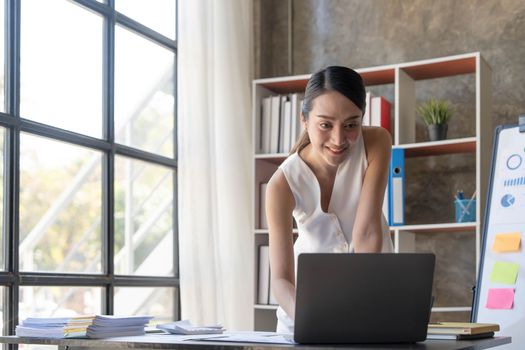 Beautiful young smiling Asian businesswoman working on laptop. Asia businesswoman working document finance and calculator in her office...