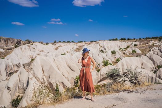 Young woman exploring valley with rock formations and fairy caves near Goreme in Cappadocia Turkey.