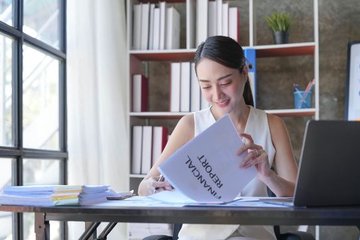 Asian Businesswoman Using laptop computer and working at office with calculator document on desk, doing planning analyzing the financial report, business plan investment, finance analysis concept...