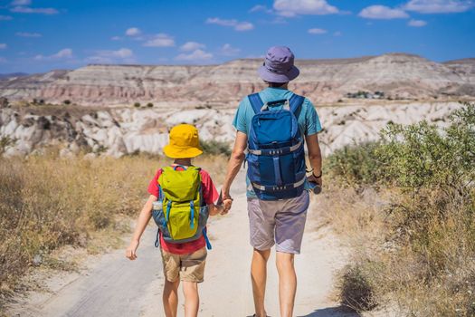 Father and son tourists exploring valley with rock formations and fairy caves near Goreme in Cappadocia Turkey.