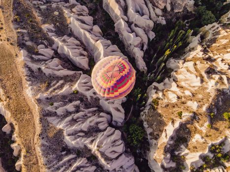 Colorful hot air balloons flying over at fairy chimneys valley in Nevsehir, Goreme, Cappadocia Turkey. Spectacular panoramic drone view of the underground city and ballooning tourism. High quality.