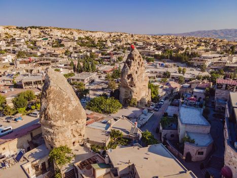 Turkish flag on the hill with typical tuff rock formations of the Cappadocia against the backdrop of a blue sky, Goreme, Turkey.