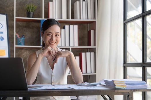 Beautiful young smiling Asian businesswoman working on laptop. Asia businesswoman working document finance and calculator in her office...