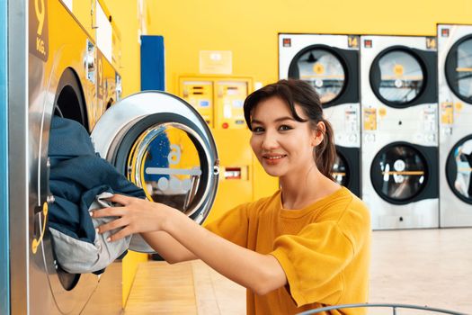 Asian people using qualified coin operated laundry machine in the public room to wash their cloths. Concept of a self service commercial laundry and drying machine in a public room.