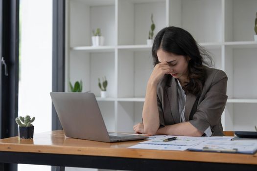 Portrait of serious young businesswoman accountant in formal wear sitting at her work place and use laptop, summarizing taxes, planning future investments, accounting at office...