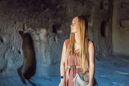 Young woman exploring valley with rock formations and fairy caves near Goreme in Cappadocia Turkey.