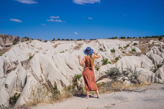 Young woman exploring valley with rock formations and fairy caves near Goreme in Cappadocia Turkey.