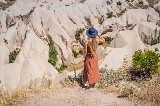 Young woman exploring valley with rock formations and fairy caves near Goreme in Cappadocia Turkey.