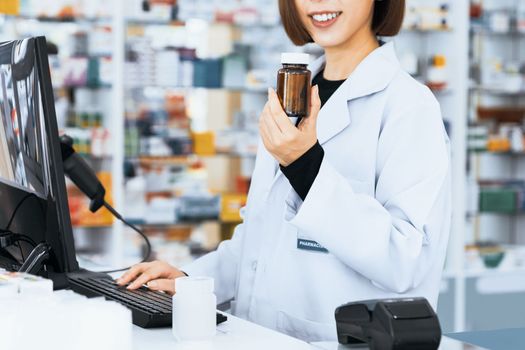 Closeup portrait of a young pharmacist and qualified pharmaceutical, medicine pill container or bottle mockup for copyspace at pharmacy. Drugstore concept with various medicine pills on