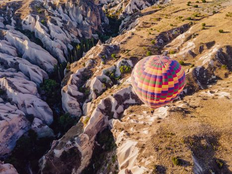 Colorful hot air balloons flying over at fairy chimneys valley in Nevsehir, Goreme, Cappadocia Turkey. Spectacular panoramic drone view of the underground city and ballooning tourism. High quality.