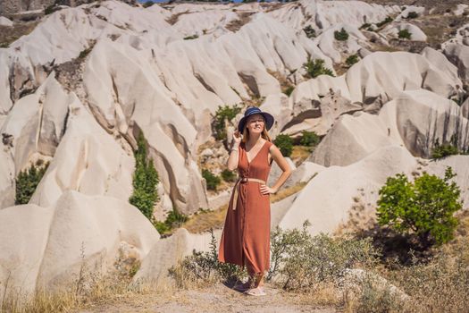 Young woman exploring valley with rock formations and fairy caves near Goreme in Cappadocia Turkey.