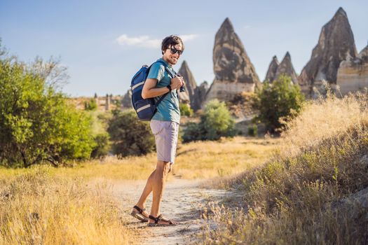 Man tourist on background of Unique geological formations in Love Valley in Cappadocia, popular travel destination in Turkey.