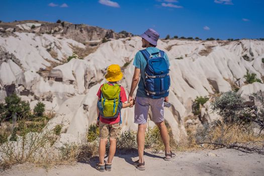 Father and son tourists exploring valley with rock formations and fairy caves near Goreme in Cappadocia Turkey.