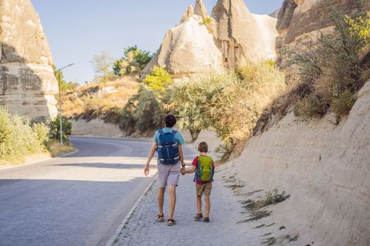 Father and son tourists on background of Unique geological formations in Love Valley in Cappadocia, popular travel destination in Turkey. Traveling with children in Turkey concept.