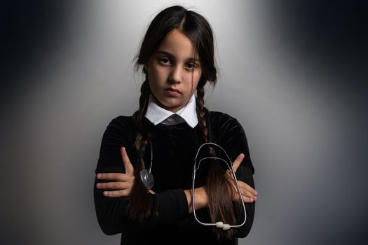 A girl with braids in a gothic style on a dark background with stethoscope