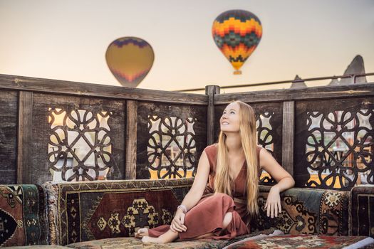 Tourist woman looking at hot air balloons in Cappadocia, Turkey. Happy Travel in Turkey concept. Woman on a mountain top enjoying wonderful view.