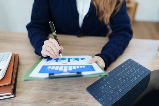 Portrait of a thoughtful Asian businesswoman looking at financial statements and making marketing plans using a computer on her desk.