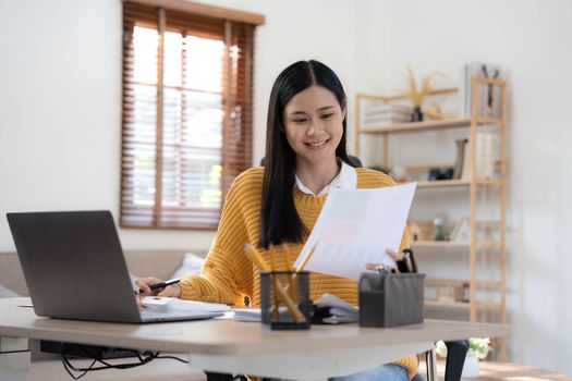 Portrait of Young Asian woman hand freelancer is working her job on computer tablet in modern home. Doing accounting analysis report real estate investment data, Financial and tax systems concept..