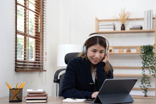 smiling girl relaxing at home She is listening to music using her laptop and wearing white headphones