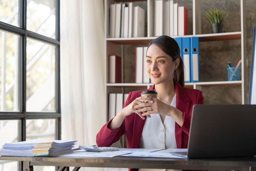 Beautiful young Asian girl working at a office space with a laptop. Concept of smart female business