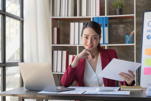 Smile Pretty business Asian woman is working her job on a laptop computer in a modern office. Doing accounting analysis report real estate investment data, Financial and tax systems concept..