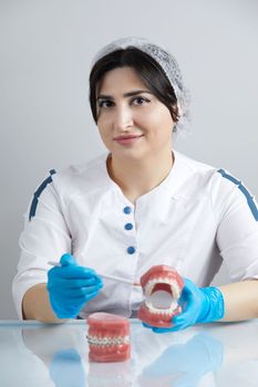 Doctor orthodontist showing model of human jaw with wire braces and aligners explaining difference