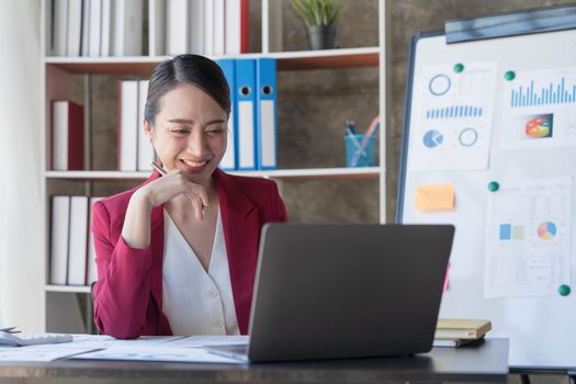 Beautiful young Asian girl working at a office space with a laptop. Concept of smart female business