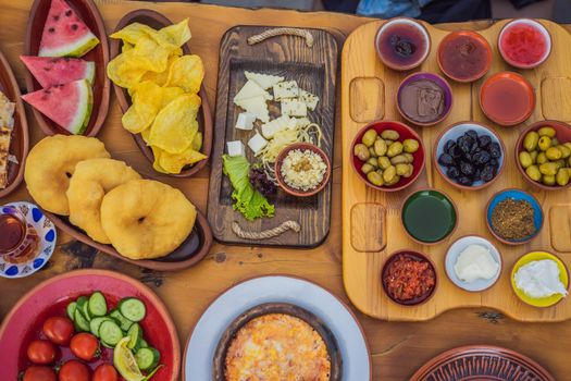 Turkish breakfast table. Pastries. Vegetables. Olives. Cheeses, fried eggs. Jams, tea in copper pot and tulip glasses. Wide composition.