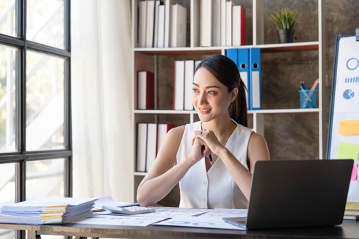 Beautiful young smiling Asian businesswoman working on laptop. Asia businesswoman working document finance and calculator in her office...