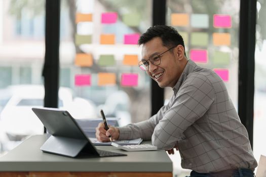 Pleasant positive businessman using digital tablet at home office.