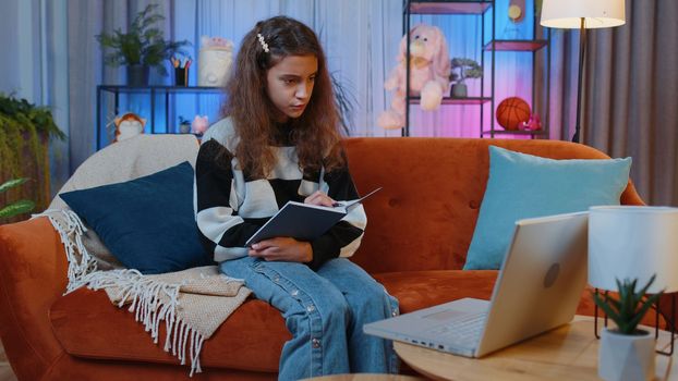Young preteen child girl student freelancer study with book at home on laptop computer making conference video webcam call talking. Online teacher e-learning in remote chat. Distance education online