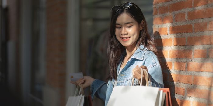 Asian fashionable woman walking at shopping mall with shopping bags while flash sale promotion.