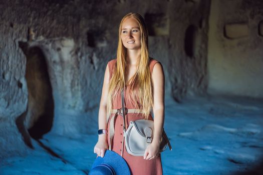 Young woman exploring valley with rock formations and fairy caves near Goreme in Cappadocia Turkey.