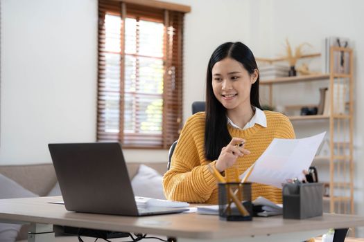 Portrait of Young Asian woman hand freelancer is working her job on computer tablet in modern home. Doing accounting analysis report real estate investment data, Financial and tax systems concept..