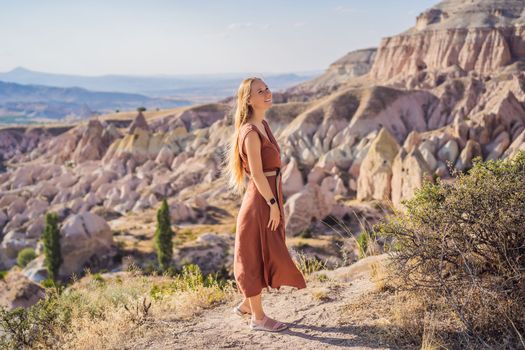 Young woman exploring valley with rock formations and fairy caves near Goreme in Cappadocia Turkey.